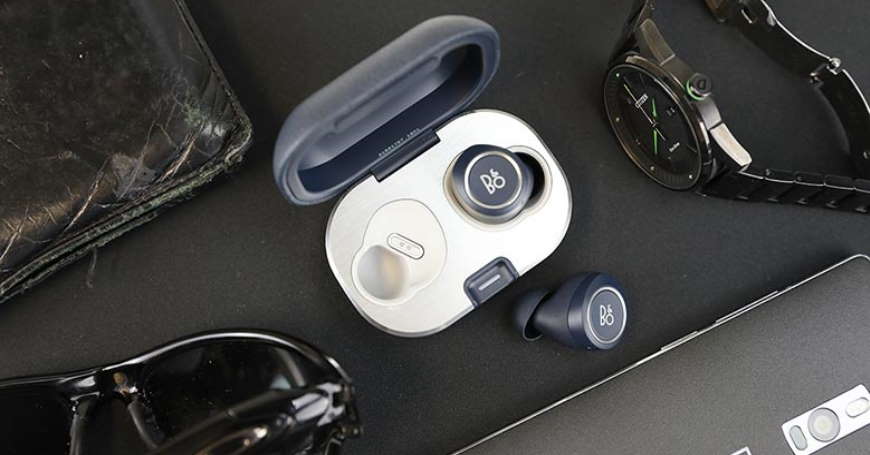 Bang & Olufsen Beoplay in-ear slušalice s kutijicom i oko njih novčanik, sat i naočale