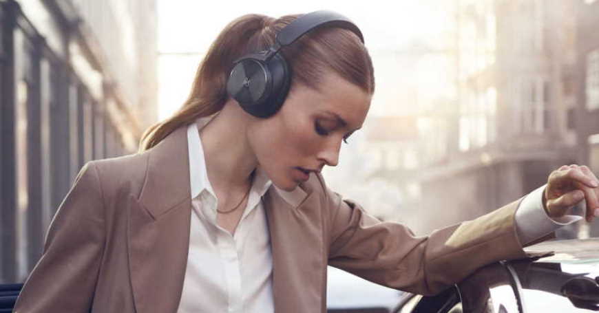 Žena u gradu sa B&O slušalicama H95 na ušima ulazi u automobil
